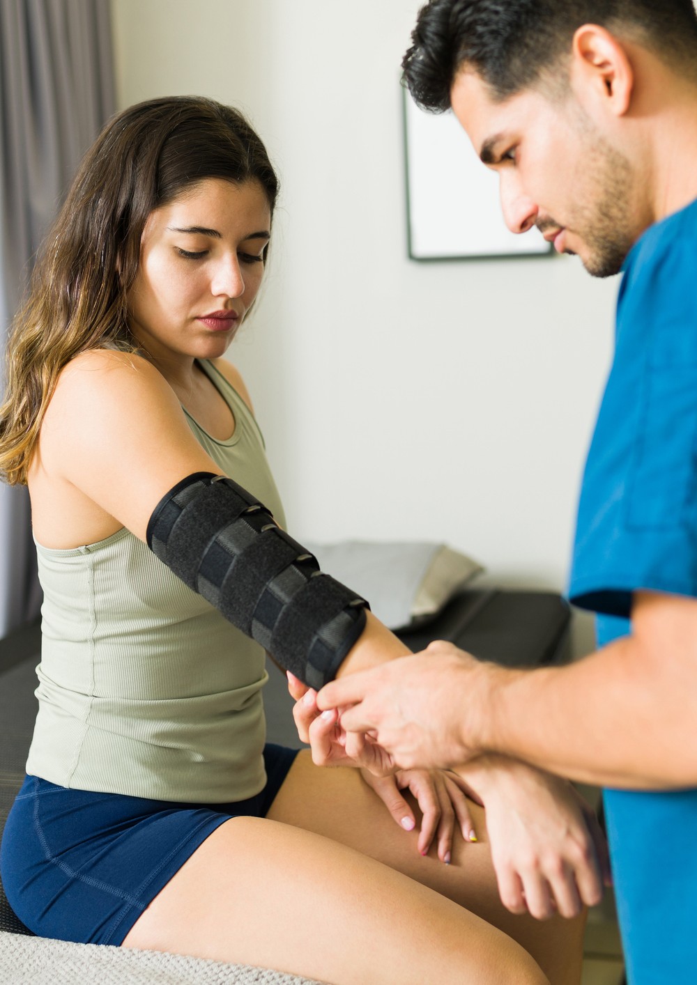 Physical therapist checking an injured arm with an elbow brace